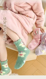 Close-up of fluffy coral fleece socks with butterfly heart patterns and elastic cuffs