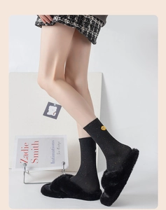Detail of black knit socks with colorful flecks and a yellow cartoon smile embroidery