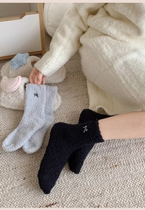 Close-up of cozy coral fleece socks featuring elegant bow embroidery and soft thick texture