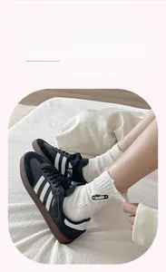 Detail of white cotton mid-calf socks featuring black safety pin embroidery and ribbed cuffs