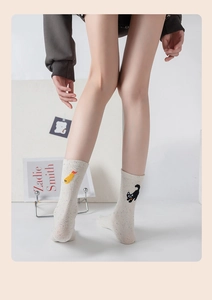 Detail of cream cotton socks featuring colorful speckled yarn and cute cartoon embroidery