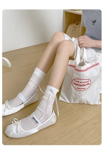 Dettaglio di calzini in cotone bianco traspirante con fiocchi e scarpe ballerine
