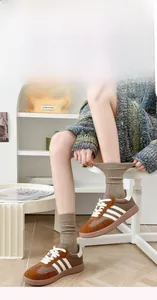 Vue détaillée de baskets rétro en daim marron avec bandes contrastées et semelle en gomme