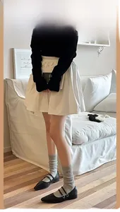 Close-up of white pleated high-waisted skirt with Japanese style bow socks and black shoes