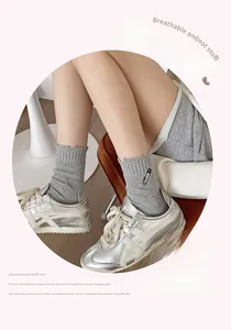 Detail of light gray ribbed cotton socks featuring unique black safety pin embroidery