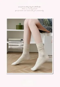 Détail de chaussettes en coton côtelé beige avec mouchetures sur sol en bois clair