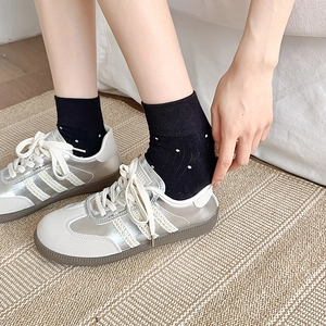 Silver leather sneakers with white stripes paired with stylish black polka dot cotton socks