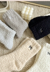 Detailed view of plush coral fleece socks featuring elegant bow embroidery accents
