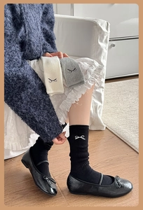 Close-up of cotton crew socks with embroidered black bow details and ribbed texture