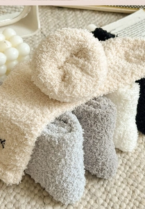 Detail of soft coral fleece socks with bow embroidery and thick plush winter texture