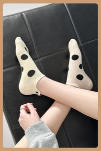 Close-up of cream cotton ankle socks featuring black polka dots and ribbed cuffs