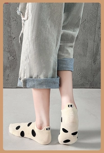 Close-up of beige cotton low cut socks with black polka dots and eye embroidery on the heel