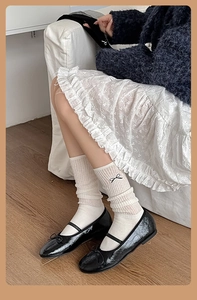 Detail of cream white ribbed crew socks with black bow accent and Mary Jane shoes