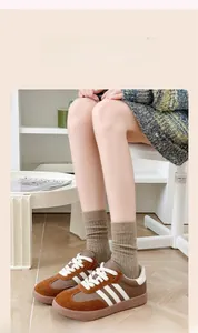 Gros plan de baskets marron rétro à rayures blanches et chaussettes en tricot