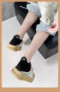 Close-up of low-cut cotton socks with eye embroidery and mesh sneakers on grey background