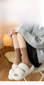 Detailed close-up of brown ribbed cotton socks with bow embroidery and plush slippers
