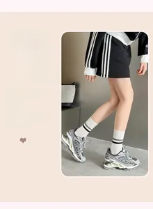 Detail view of white cotton mid-calf socks with athletic stripes and chunky sneakers