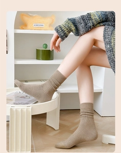 Gros plan de chaussettes mi-mollet en tricot côtelé kaki dans un décor minimaliste