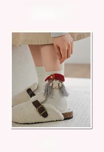 Detail of white ribbed cotton mid-calf sock featuring a 3D cartoon doll with red hat