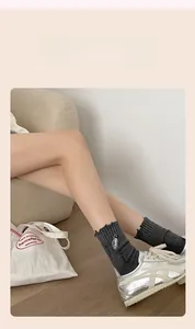 Detail of dark grey ribbed socks featuring a unique white safety pin embroidery