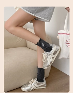 Detailed view of dark grey distressed socks with safety pin embroidery and silver sneakers