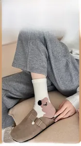 Detail shot of white cotton mid-tube socks featuring a cute brown cartoon bear pattern