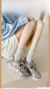 Sneakers chunky argento con dettagli rosa indossate con calze a righe in cotone