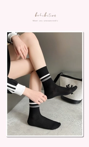 Detail of black combed cotton mid-tube socks featuring white and grey striped knit cuffs