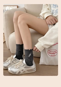 Close-up of grey ribbed socks with distressed frayed cuffs and safety pin embroidery