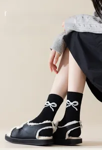 Detail of black slub yarn mid-calf socks with white bow pattern and thick knit texture