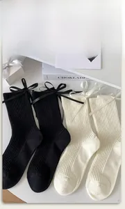 Close-up of ribbed knit socks with silk bows on gift box and book background