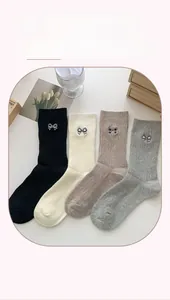 Detail of four pairs of cotton socks in black, cream, coffee and grey with bow embroidery