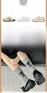 Détail de chaussettes grises à motifs nœuds floqués noirs portées avec des chaussures