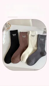 Detail of ribbed cotton mid-calf socks with ruffle trim and silver glitter bow accents