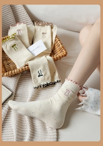 Detail of embroidered bow on cream speckled socks with delicate lettuce trim edges