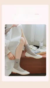 Detail of grey ribbed cotton socks with black bow embroidery and white ballet flats