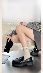 Detail of cream rib-knit socks featuring plush heart patches and chunky black loafers