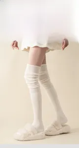 Detailed view of cream over-the-knee socks with ribbed texture and hand-stitched toes