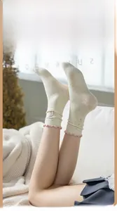 Close-up of beige polka dot crew socks with pink ruffled edge and rabbit embroidery