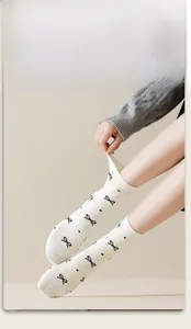 Detail of cream cotton crew socks featuring black bow patterns and colorful speckle textures