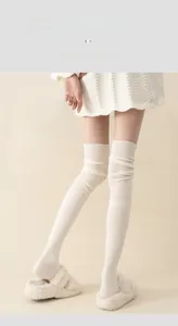 Detail of cream cotton over-knee socks featuring vertical ribbed knit texture for women