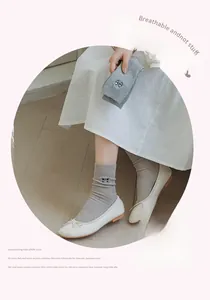 Detail of grey ribbed cotton socks featuring elegant black bow embroidery and soft texture
