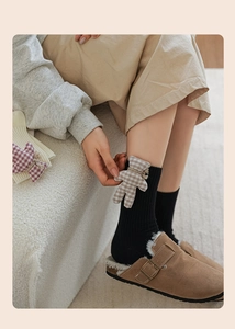 Detail shot of cute plaid 3D bear doll on black cotton ribbed mid-tube socks