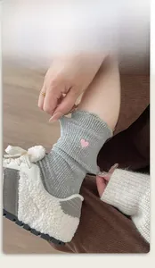 Gros plan de chaussettes grises en coton avec broderie cœur rose et bordure élastique
