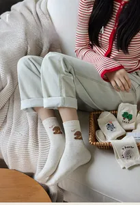 Close-up of cute cartoon bear and sheep embroidery on cozy white speckled mid-calf socks