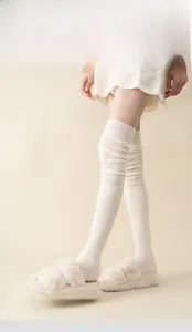 Detailed knit texture of white over-the-knee cotton socks with ribbed patterns and heel padding