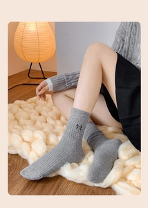 Detail of grey ribbed cotton sock with delicate black embroidered bow on the cuff