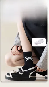 Close-up detail of black cotton crew socks featuring white bow embroidery and dot yarn
