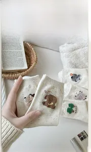 Detailed view of beige cotton socks with colorful flecks and cute 3D bear embroidery