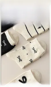 Close-up of bow-knot socks in black and cream featuring stylish speckled yarn texture